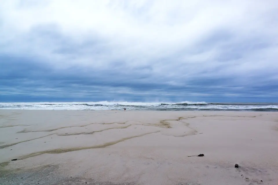 A moody overcast ocean over wet sand flats at Cupsogue Beach.